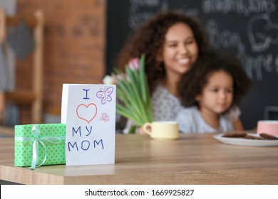 Greeting card and gift for Mother's Day on table in kitchen