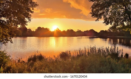 Schöner und romantischer Sonnenuntergang an einem See in gelben und orangefarbenen Farben