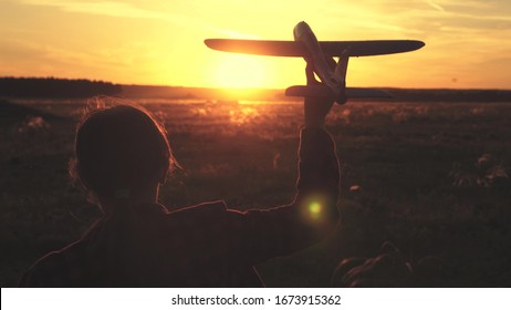 Cô gái hạnh phúc chạy với một chiếc máy bay đồ chơi trên cánh đồng dưới ánh sáng hoàng hôn. trẻ em chơi máy bay đồ chơi. ước mơ thiếu niên bay và trở thành một phi công. cô gái muốn trở thành một phi công và phi hành gia. Chuyển động chậm