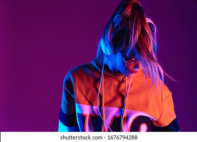 Teen girl wear headphones listen music, dancing standing at purple background.