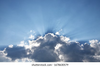 Donkere wolken met zonnestralen boven een blauwe lucht