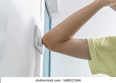 using elbow to turn on the light switch to avoid the contact with viruses on the frequently touched surfaces