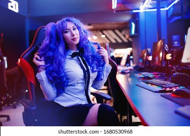 Woman gamer with headphones playing online games on computer and monitor, neon color.