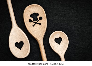 黒いスレートの背景にハートとスケルトンを持つキッチンの木製スプーン、トップビュー。幸せな素敵な料理のバレンタインデーのコンセプト