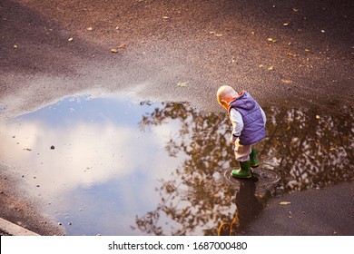Niño camina en el charco después de la lluvia