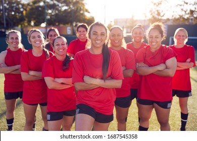 Retrato de un equipo de fútbol femenino sonriente entrenando para un partido de fútbol en una cancha de césped artificial al aire libre