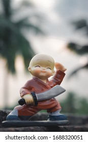 Cute sweet plastic Doll standing with sword and king costume on skateboard dress as wonder prince in action adventure. Close up portrait. Outdoor childhood fun play leisure game toddler background.