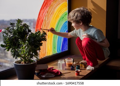 みんな元気でいよう。家の子供は窓に虹を描きます。パンデミックコロナウイルスの自己隔離検疫に関するフラッシュモブ社会コミュニティ。子供たちはアーティストの絵の具を作成し、創造的な休暇を過ごします