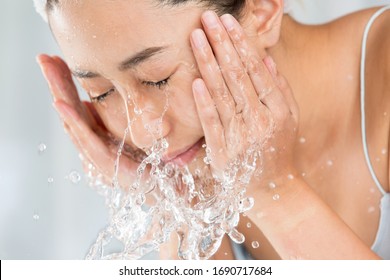 部屋で顔を洗う若い女性。