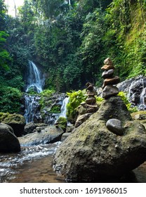 Ustronny tajny naturalny wodospad Pengibul, z sztucznym stosem skały równoważącej na Bali, Indonezja