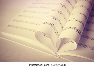 Hart gemaakt van boekpagina's met muzieknoten op tafel, ruimte voor tekst