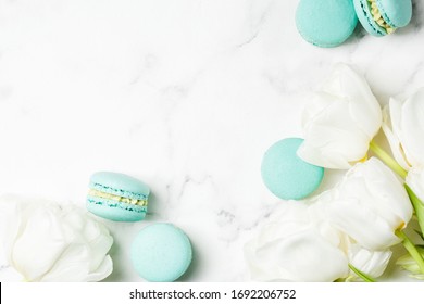 Tulpenblumenstrauß mit blauen Makronenbonbons auf hellem Marmortisch. Glückliches Muttertagskonzept. Grußdraufsichthintergrund mit Kopienraum