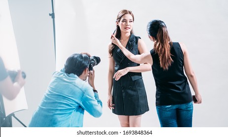 The professional photoshoot set indoor studio with Asian model actress, make up artist and photographer, behind the scene in photography industry, professional occupation, portrait in white background