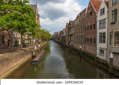 Canal de agua entre casas con camino a lo largo de casas en Dordrecgt en Holanda. El camino está bordeado de árboles.