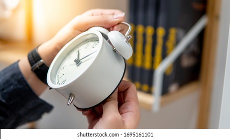 Männliche Hand, die die Zeit auf der weißen Uhr anpasst oder ändert. Zeitmanagement-Konzept.