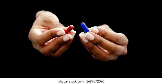 أيدي امرأة سوداء تقدم حبوب حمراء وزرقاء على خلفية سوداء. مفهوم الحقيقة القبيحة مقابل الكذبة الجميلة، الواقع مقابل الخيال.