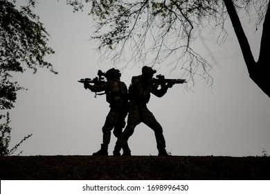 Silhouetten von Armeesoldaten gegen die Sonne, Marinesoldatenteam in Aktion, Feuer und Rauch umzingelt, mit Sturmgewehr und Maschinengewehr geschossen, Feind angegriffen