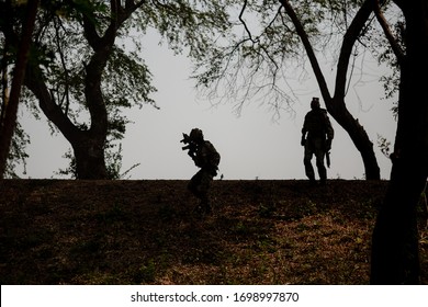 Silhouetten von Armeesoldaten gegen die Sonne, Marinesoldatenteam in Aktion, Feuer und Rauch umzingelt, mit Sturmgewehr und Maschinengewehr geschossen, Feind angegriffen