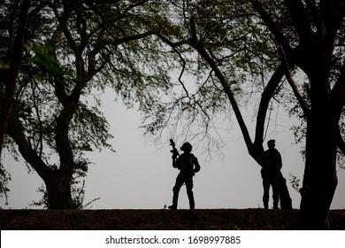 Silhouetten von Armeesoldaten gegen die Sonne, Marinesoldatenteam in Aktion, Feuer und Rauch umzingelt, mit Sturmgewehr und Maschinengewehr geschossen, Feind angegriffen