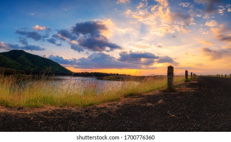 Panoramic landscape view of sunset or sunrise sky clouds over lake dam mountain and asphalt road. Concept of country side landscape and nature view
