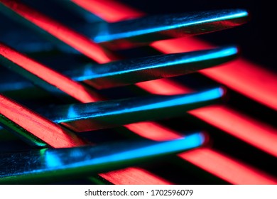 Close-up of prongs of a dining fork, illuminated in red,  blue and green. Abstract object, isolated against a black background. Selective focus with bokeh.