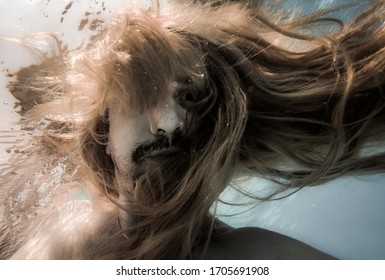 Foto artística fora de foco debaixo d'água com homem de cabelo comprido nadando com bolhas na água, atmosfera subaquática escura com criatura abissal humana de pesadelo como sereia com barba