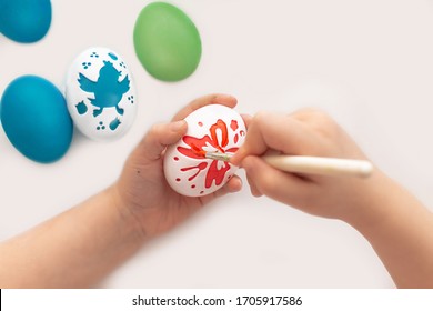 Children's hands of a girl draw shapes on eggs with a brush. happy Easter. Paint the eggs with bright colors.Draw a picture on the eggs for the holiday. Mock up