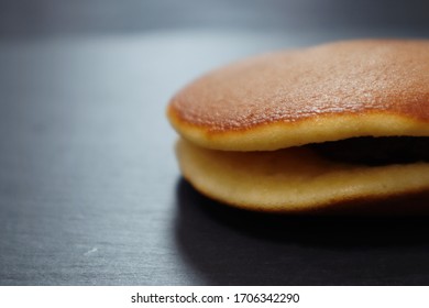 日本の小豆パンケーキまたは「どら焼き」と黒の背景にお茶