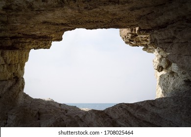 Entrada del agujero de piedra o apertura en la pared de la cueva de roca mirando al cielo y al mar