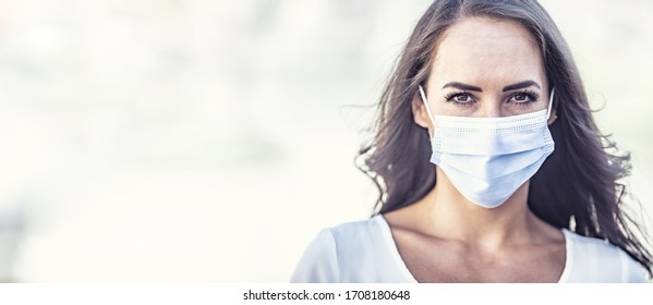 Serious looking young woman wearing a disposable face mask on an isolated background, covering the right half of the picture.