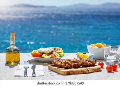 Grieks voedselconcept met boerensalade en souvlaki-spiesjes voor de sprankelende, blauwe Egeïsche zee in de zomer