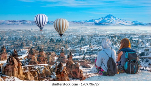 Heißluftballon fliegt über das spektakuläre Kappadokien neben den Erciyes-Bergen - Mädchen beobachten den Heißluftballon auf dem Hügel von Kappadokien - Göreme, Türkei