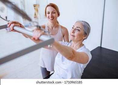 Pilates aerobe vrouwelijke instructeur training met fitte oudere vrouw in cadillac fitness oefening. Rehabilitatieconcept voor een actieve en gezonde levensstijl.