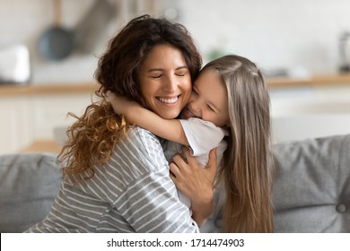 Liebevolle schöne junge Frau, die kleine Tochter des Vorschulkindes kuschelt und Glück fühlt. Nettes kleines Mädchen, das liebevolle Mama umarmt, sich dankbar fühlt und zarte süße Zeit zu Hause genießt.