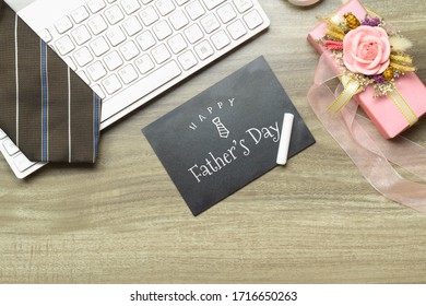 Mensaje del día del padre feliz en la pizarra. Composición plana en el escritorio con teclado de computadora, corbata y boex de regalo.