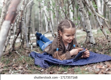 Niña chateando por teléfono móvil en la cabaña de madera construida en la cabaña en el bosque de abedules salvajes durante su caminata social distante en el tiempo de cierre, caminando al aire libre, estilo de vida activo al aire libre