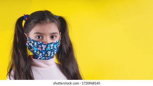Little cute girl with colorful mask on yellow background. stop covid-19. Stay at home. Quarantine. Coronavirus.Girl plays a doctor. education and occupation concept. stay self