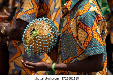 'n Nabyfoto wys hoe 'n tromspeler 'n African Shekere kalbasse perkussie-instrument speel terwyl hy in 'n optog marsjeer tydens 'n kente yam-fees in Ghana, Wes-Afrika