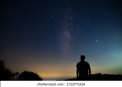 Silueta borrosa de un hombre observando el cielo estrellado con la vía láctea
