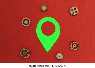 Un cartel de geolocalización verde rodeado de engranajes de madera sobre un fondo rojo. Tecnología de rastreo de ubicación.