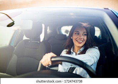 Mujer feliz conduciendo un auto y sonriendo. Linda mujer morena feliz éxito joven está conduciendo un coche. Retrato de una conductora feliz manejando un auto con cinturón de seguridad