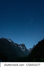 Una toma vertical de montañas bajo un cielo azul oscuro lleno de estrellas.