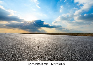 Strada asfaltata vuota e splendide nuvole al tramonto.