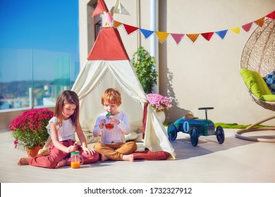 cute kids playing toys on summer patio, drinking fresh lemonade