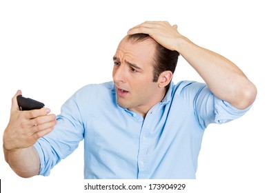 Closeup portrait of shocked man feeling head, surprised he is losing hair, receding hairline or seeing bad news on cellphone, isolated on white background. Negative facial expressions, emotion feeling