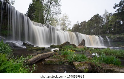 Wasserfall im Unterlauf des Flusses Keila am nordestnischen Klint. Keila-Joa Castle Schloss Fall (Keila Joa. Glatte Oberfläche, gebrochene und gefallene Felsen und Gras, bewölkte Himmelslandschaft. Estland.