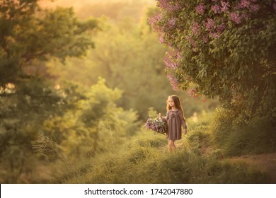 Het langharige meisje loopt in een bloeiende lentetuin met een mand met seringen. Afbeelding met selectieve aandacht.