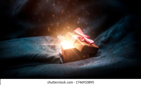 Dárková krabička na tmavém magickém pozadí se světlým bokeh. Slavnostní pozadí, magická krabička s dárkem. Tmavé abstraktní pozadí se zlatým bokeh.