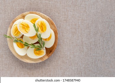 Vista superior de huevos cocidos en un tazón de madera sobre fondo de tela de algodón con espacio para copiar. Dieta del huevo cocido.