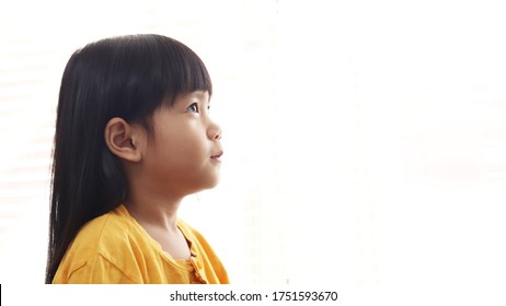 Cute little Asian baby girl looking up thinking something isolated on white background, side profile. Hope concept with copy space